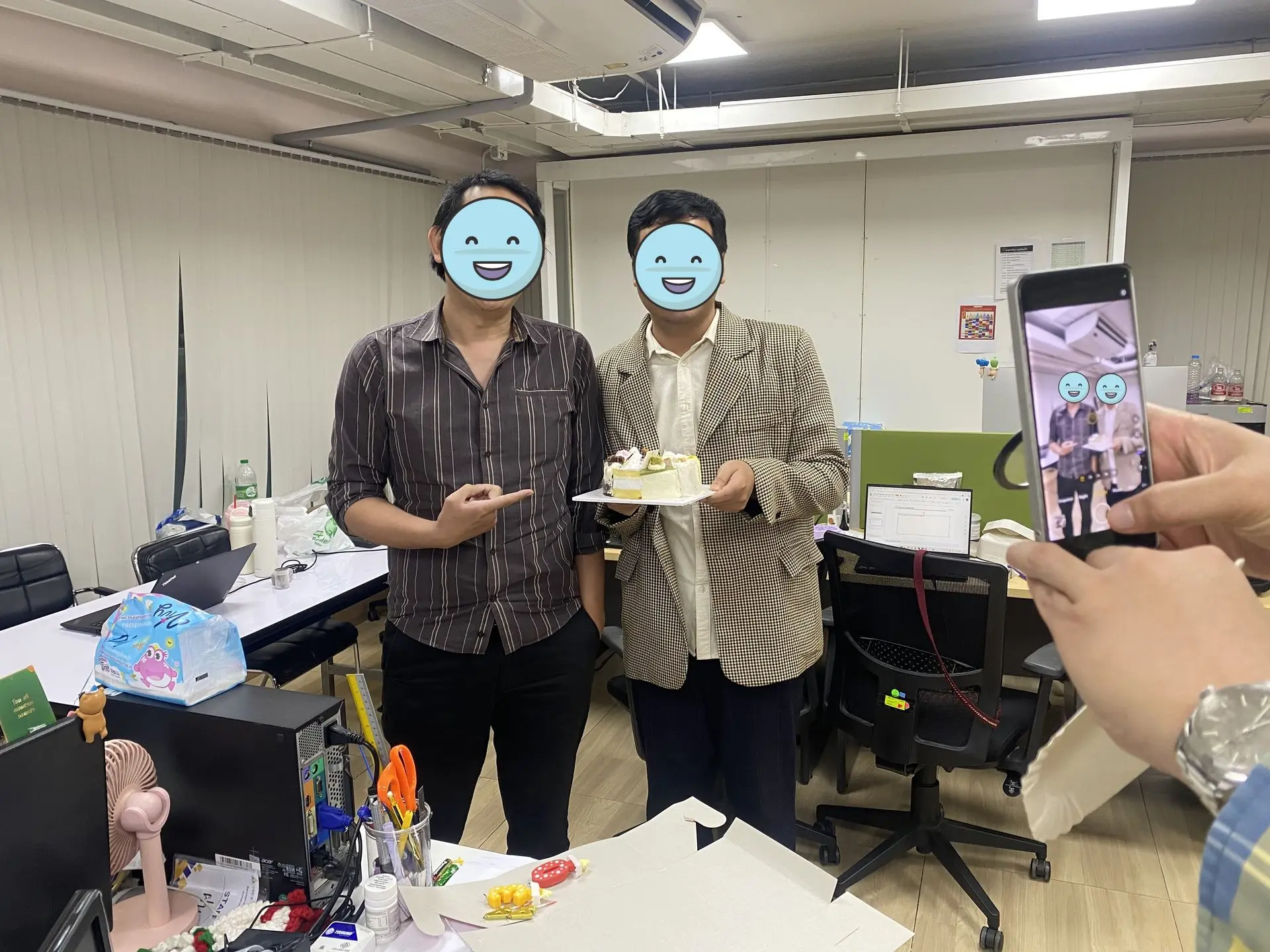 Two V Group colleagues who share the same birthday celebrating with a cake at the office